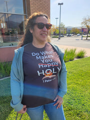 Women wearing a Brown Christian T-shirt with white bold lettering that reads "Do what make you happy holy, 1 Peter 1:15".  The word happy is crossed out and there's a holy flame and a bible image behind the holy.