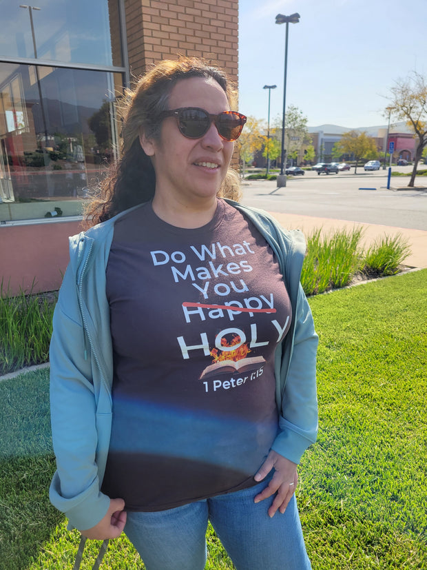 Women wearing a Brown Christian T-shirt with white bold lettering that reads "Do what make you happy holy, 1 Peter 1:15".  The word happy is crossed out and there's a holy flame and a bible image behind the holy.